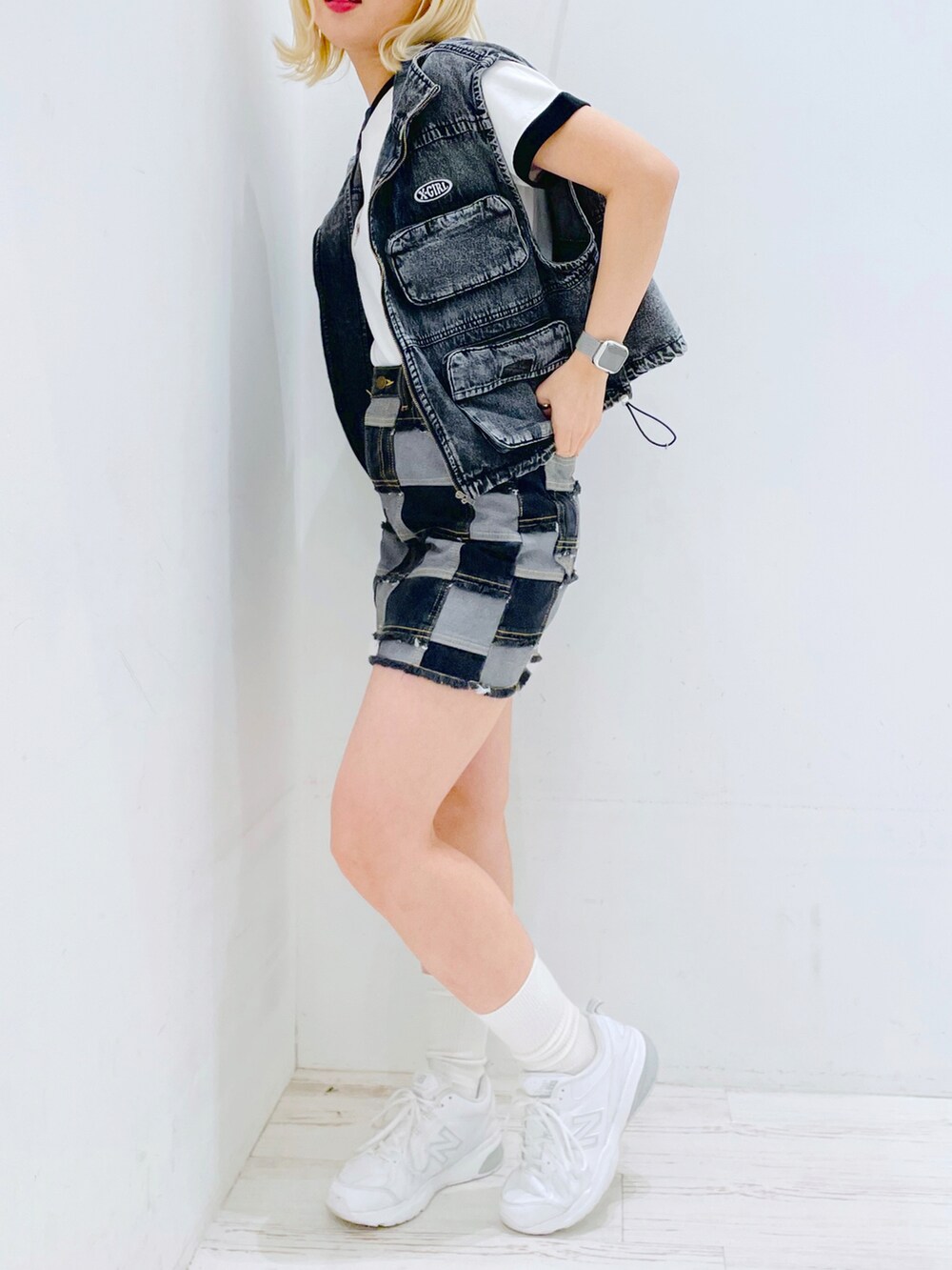 ブラック系のデニムスカート、ホワイト系のTシャツ/カットソー、ブラック系のベストを着用したレディースの春コーディネートの2枚目の写真