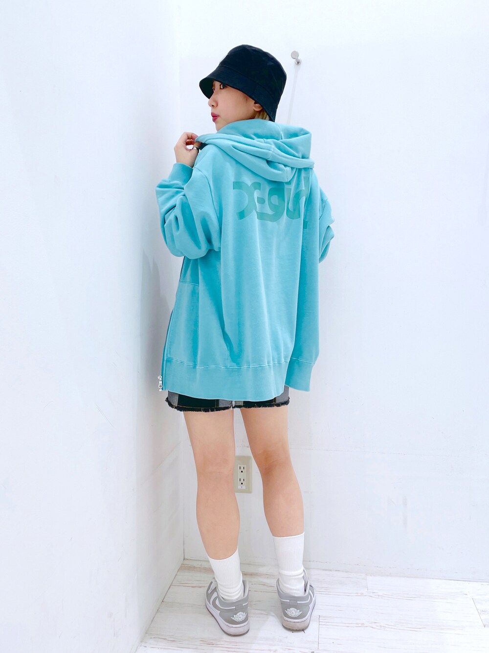 ブラック系のデニムスカート、レッド系のタンクトップ、グリーン系のパーカーを着用したレディースの春コーディネートの4枚目の写真