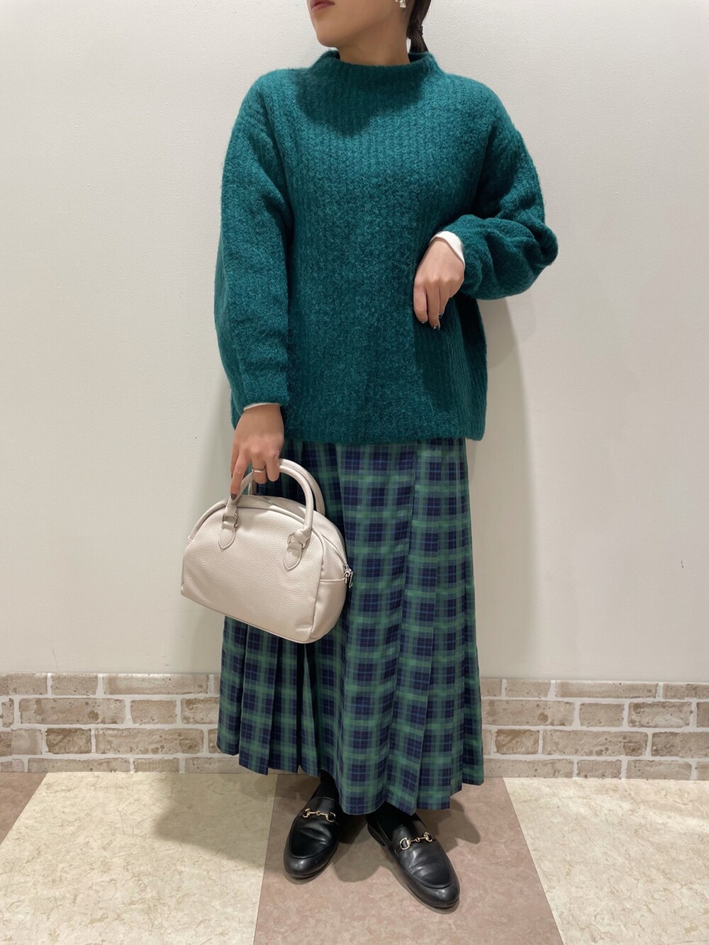 グリーン系のニット/セーター、グリーン系のスカート、ベージュ系のボストンバッグを着用したレディースの冬コーディネートの3枚目の写真