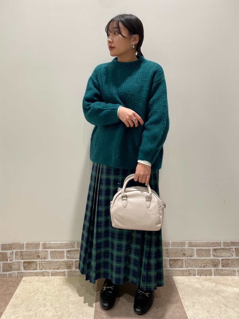 グリーン系のニット/セーター、グリーン系のスカート、ベージュ系のボストンバッグを着用したレディースの冬コーディネートの2枚目の写真