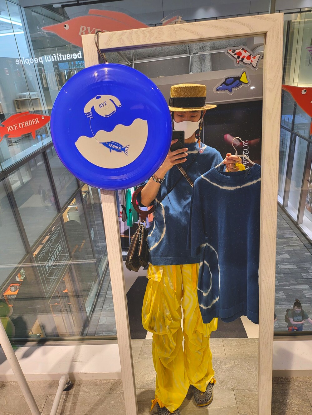 イエロー系のパンツ、ブルー系のニット/セーター、グリーン系のバッグを着用したメンズの秋コーディネートの2枚目の写真