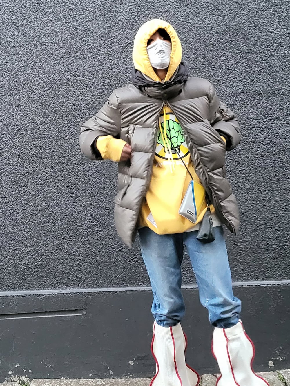 イエロー系のパーカー、ブラウン系のブーツ、ホワイト系のレッグウォーマーを着用したメンズの冬コーディネートの2枚目の写真