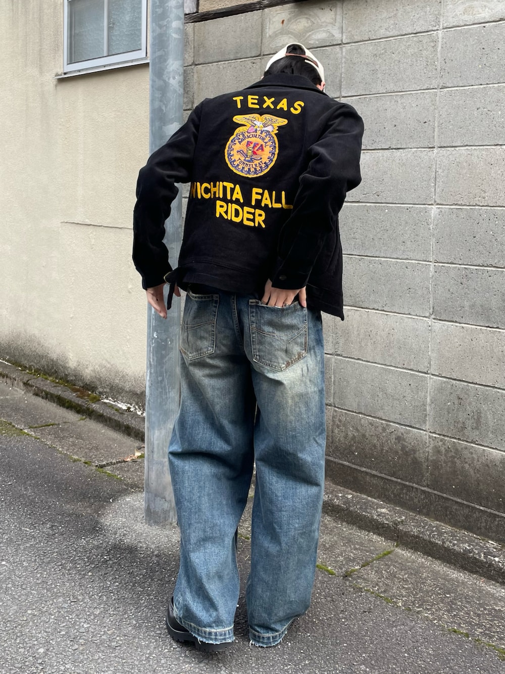 グレー系のスウェット、ブラック系のミリタリージャケット、ブルー系のデニムパンツを着用したメンズの春コーディネートの2枚目の写真