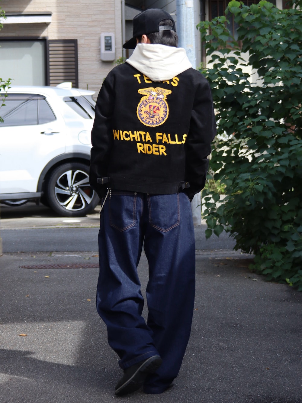 ベージュ系のパーカー、ホワイト系のタンクトップ、ブラック系のミリタリージャケットを着用したメンズの秋コーディネートの3枚目の写真