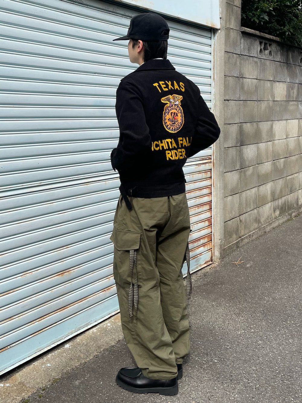 ブラック系のミリタリージャケット、グリーン系のカーゴパンツ、ブラック系のドレスシューズを着用したメンズの春コーディネートの4枚目の写真