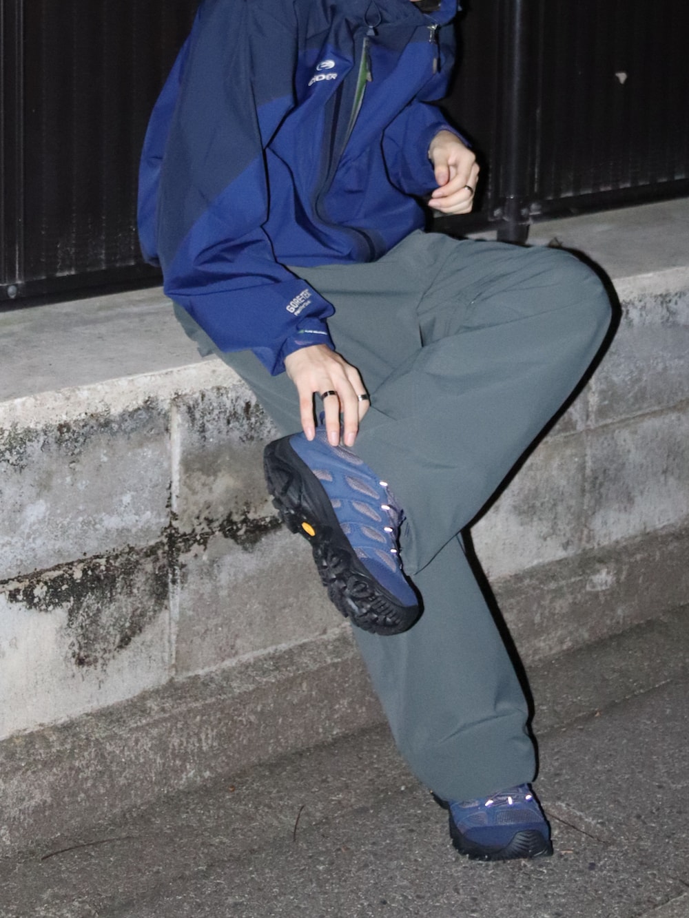 グレー系のスニーカー、ブルー系のマウンテンパーカー、グリーン系のカーゴパンツを着用したメンズの秋コーディネートの3枚目の写真