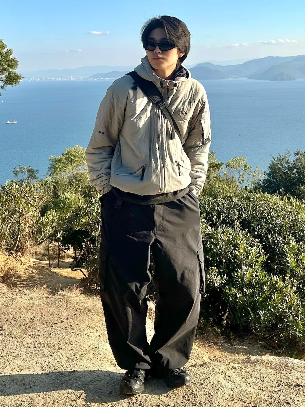 ブラック系のスニーカー、その他のメッセンジャーバッグ、ブラック系のカーゴパンツを着用したメンズの冬コーディネートの2枚目の写真