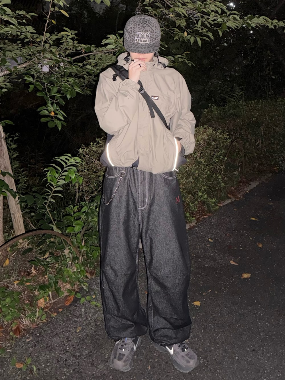 グレー系のスニーカー、ベージュ系のマウンテンパーカー、ブラック系のデニムパンツを着用したメンズの秋コーディネートの2枚目の写真