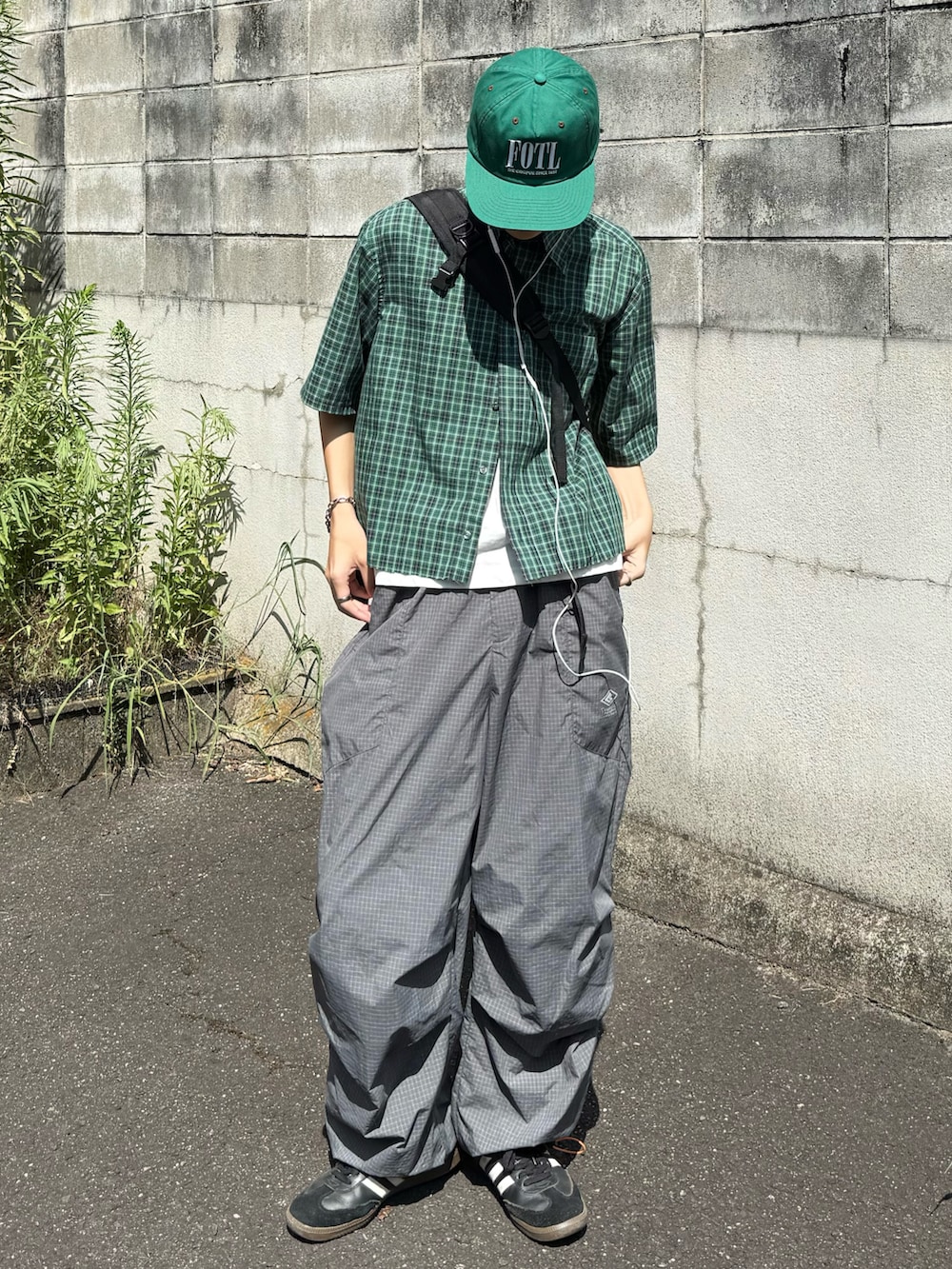 ホワイト系のタンクトップ、ブラック系のスニーカー、グレー系のカーゴパンツを着用したメンズの夏コーディネートの2枚目の写真