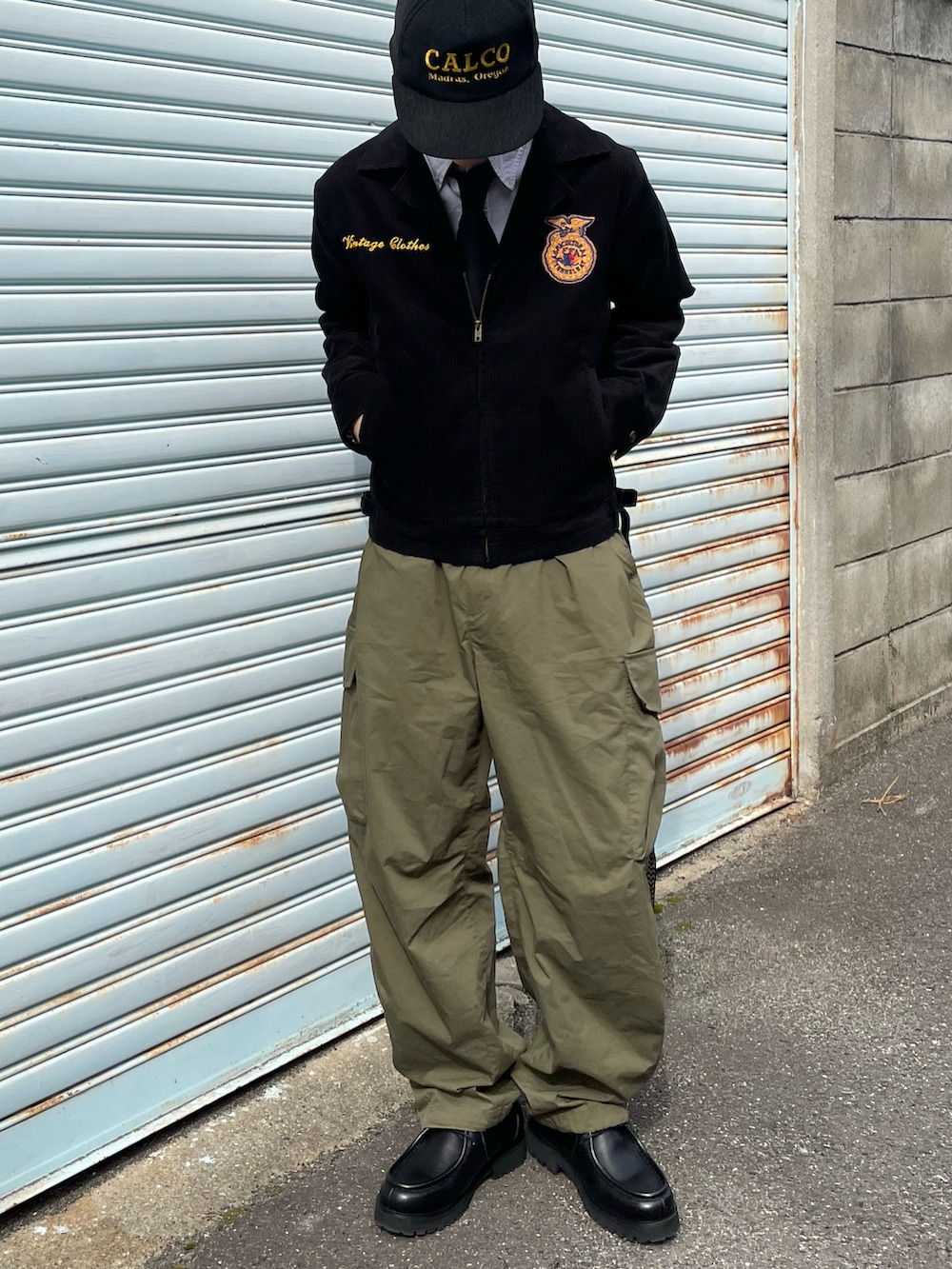 ブラック系のミリタリージャケット、グリーン系のカーゴパンツ、ブラック系のドレスシューズを着用したメンズの春コーディネートの3枚目の写真