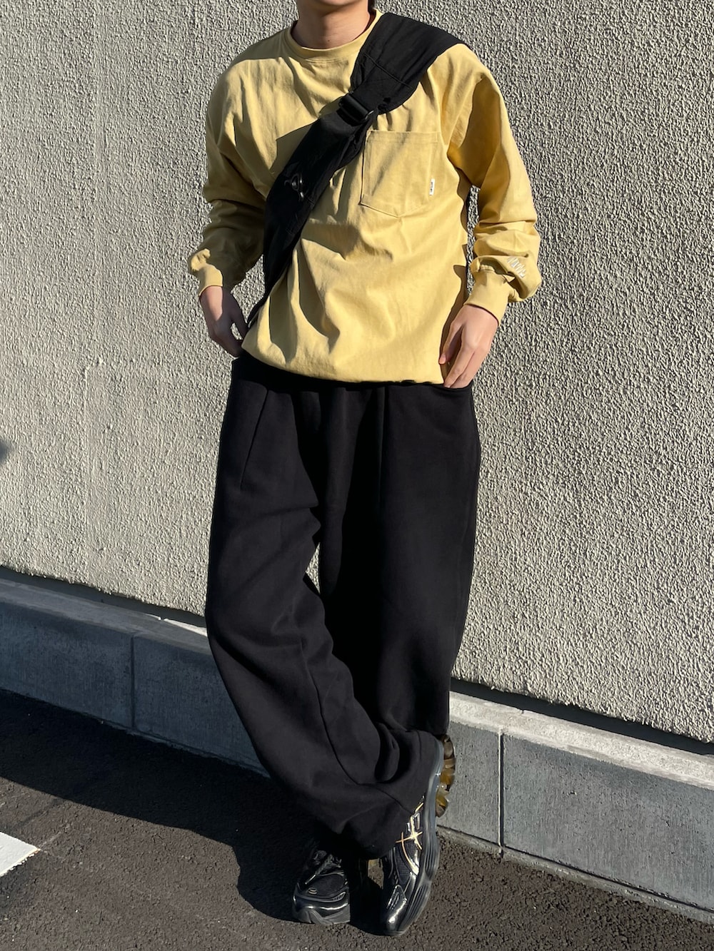 ブラック系のスウェットパンツ、イエロー系のTシャツ/カットソー、ブラック系のショルダーバッグを着用したメンズの春コーディネートの3枚目の写真