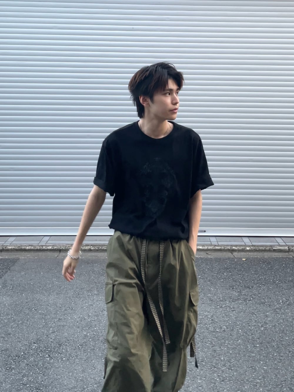 グリーン系のカーゴパンツ、ブラック系のTシャツ/カットソー、ブラック系のブーツを着用したメンズの夏コーディネートの4枚目の写真