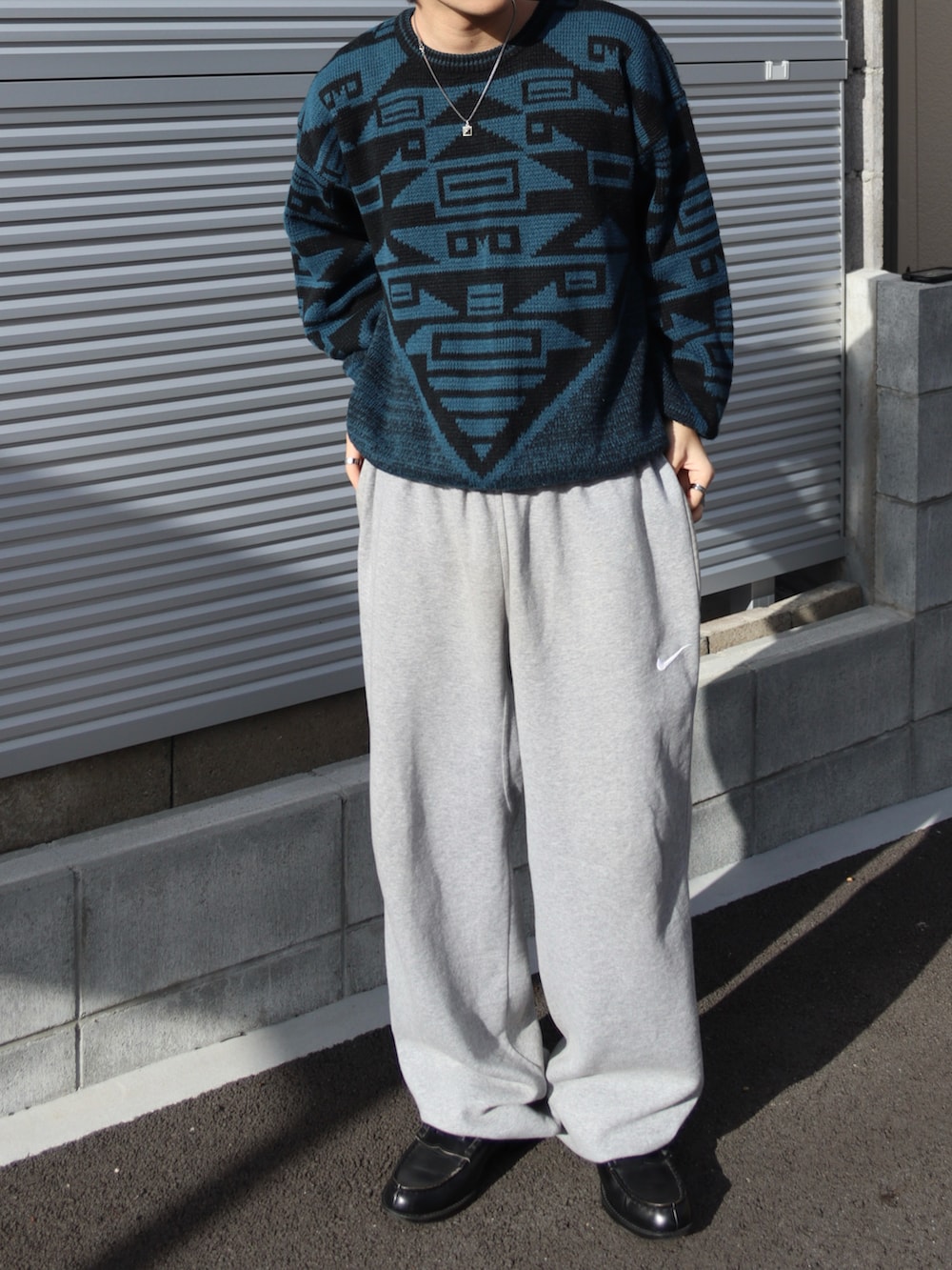 ブラック系のローファー、ブルー系のニット/セーター、グレー系のスウェットパンツを着用したメンズの秋コーディネートの3枚目の写真