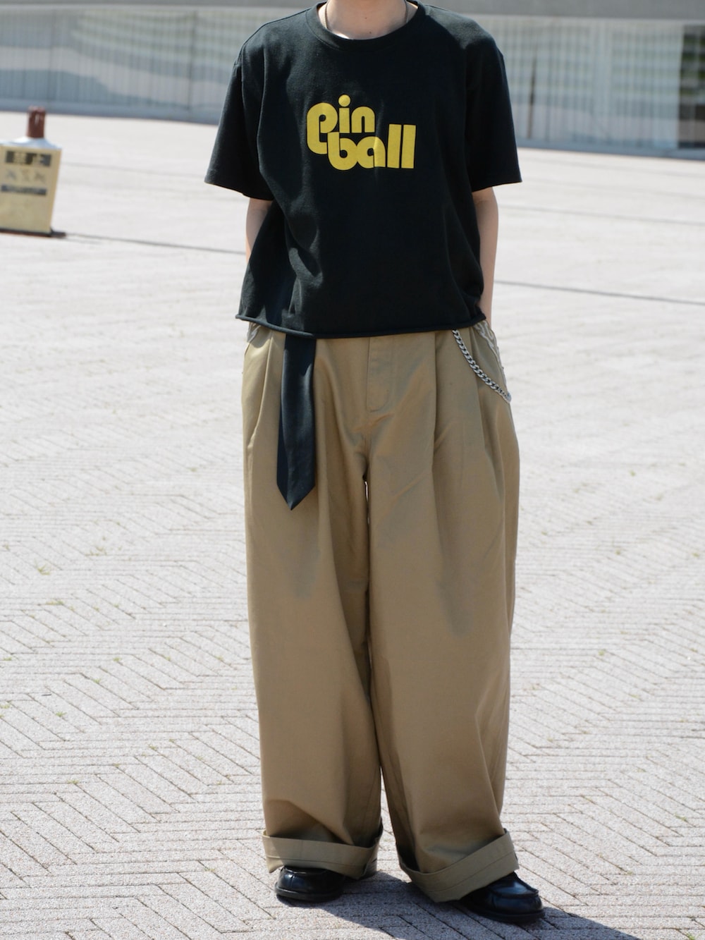 ベージュ系のチノパンツ、ブラック系のTシャツ/カットソー、ブラック系のローファーを着用したメンズの夏コーディネートの4枚目の写真