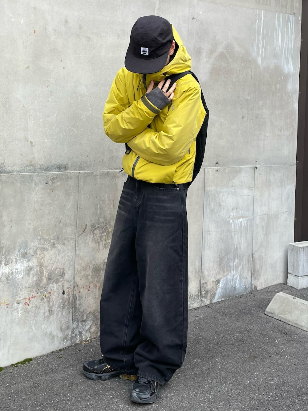 ブラック系のショルダーバッグ、ブラック系のスニーカー、イエロー系のジャケット/アウターを着用したメンズの冬コーディネートの3枚目の写真