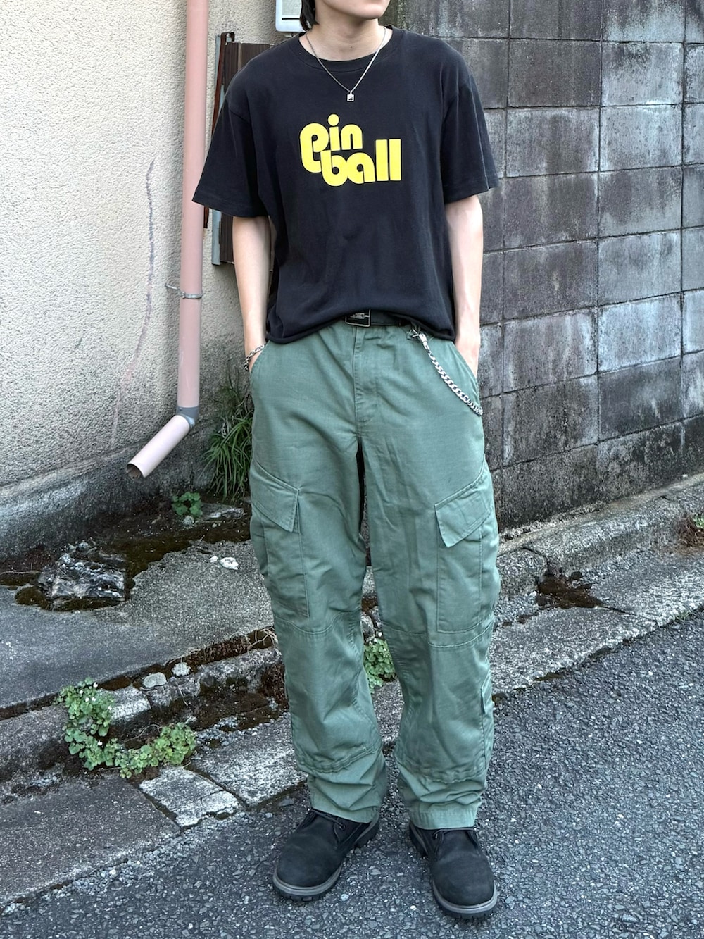 ブラック系のTシャツ/カットソー、グリーン系のカーゴパンツ、ブラック系のブーツを着用したメンズの秋コーディネートの3枚目の写真