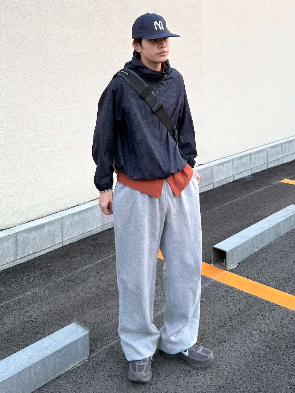 オレンジ系のシャツ/ブラウス、グレー系のスニーカー、ブルー系のマウンテンパーカーを着用したメンズの夏コーディネートの2枚目の写真