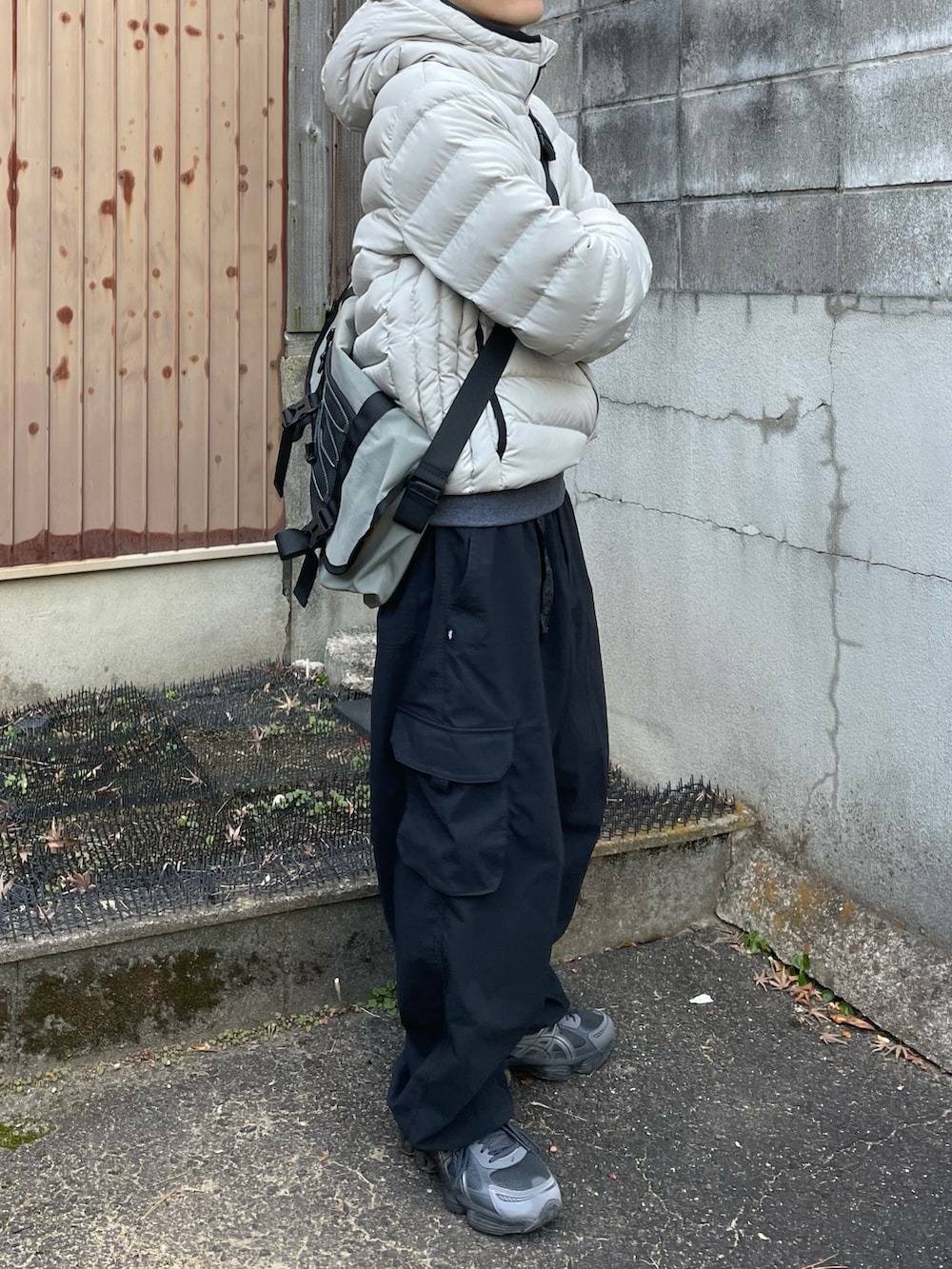 グレー系のスウェット、グレー系のメッセンジャーバッグ、ブラック系のカーゴパンツを着用したメンズの冬コーディネートの3枚目の写真