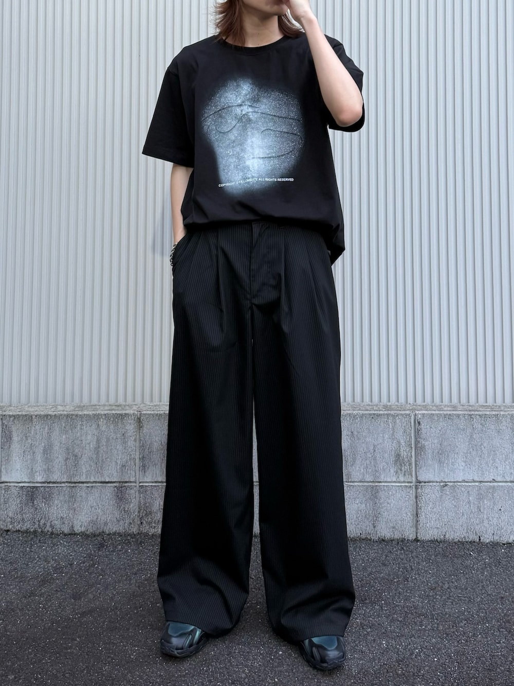 ブラック系のTシャツ/カットソー、ブラック系のスラックス、ブラック系のスニーカーを着用したメンズの夏コーディネートの3枚目の写真