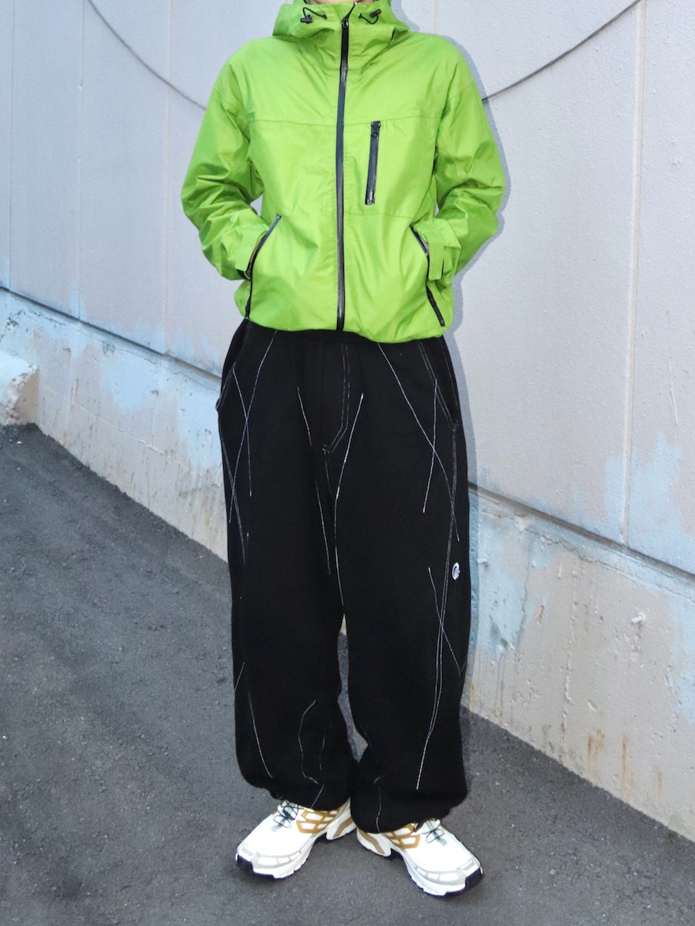 ホワイト系のスニーカー、グリーン系のマウンテンパーカー、ブラック系のスウェットパンツを着用したメンズの秋コーディネートの3枚目の写真