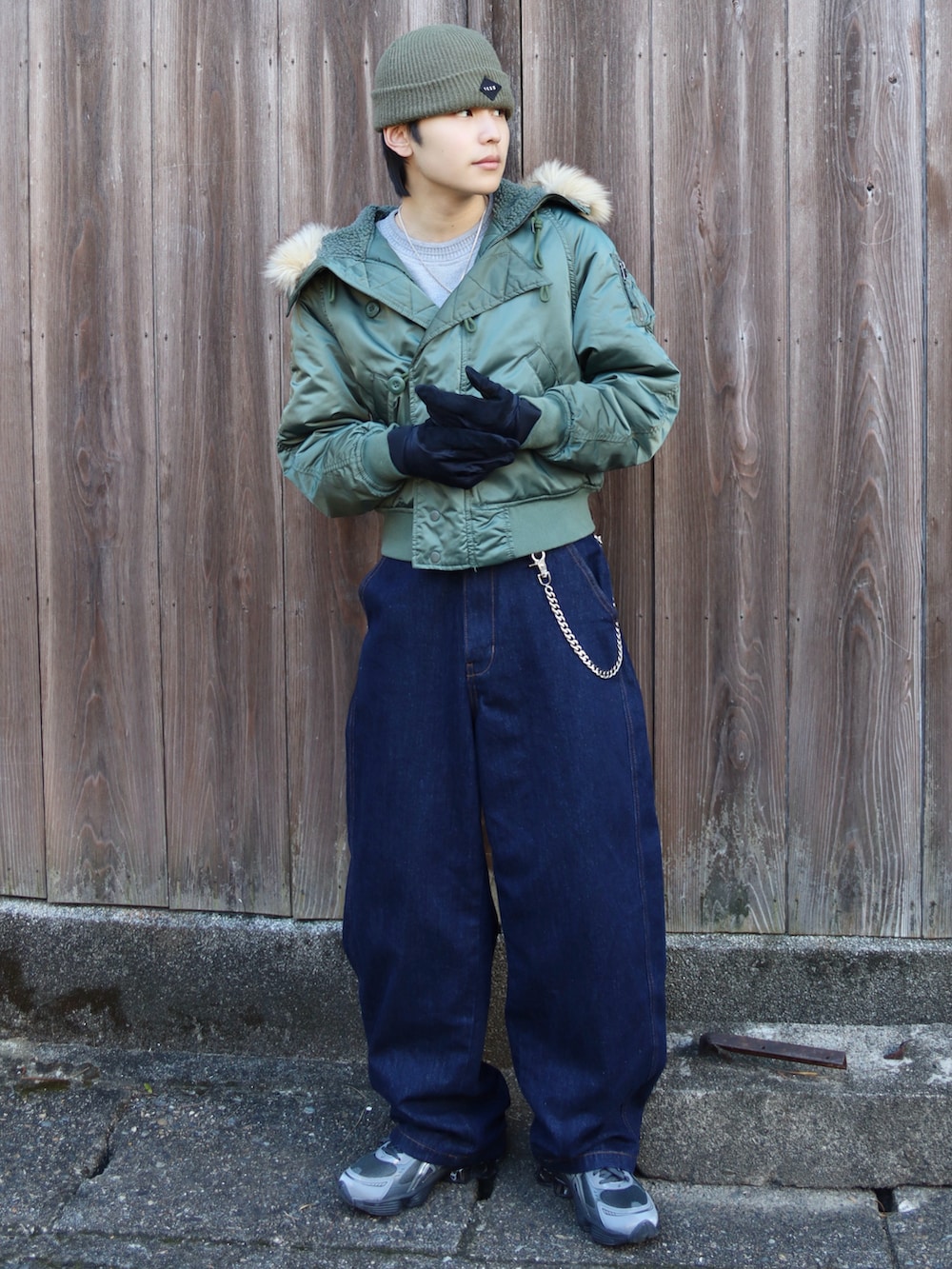 グレー系のスニーカー、グレー系のトップス、グリーン系のミリタリージャケットを着用したメンズの秋コーディネートの2枚目の写真