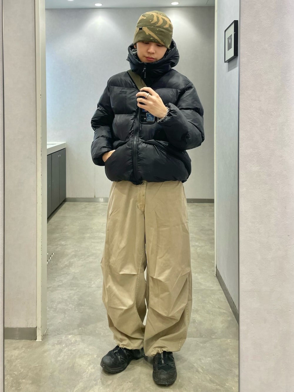 ベージュ系のカーゴパンツ、グリーン系のショルダーバッグ、ブラック系のスニーカーを着用したメンズの冬コーディネートの2枚目の写真
