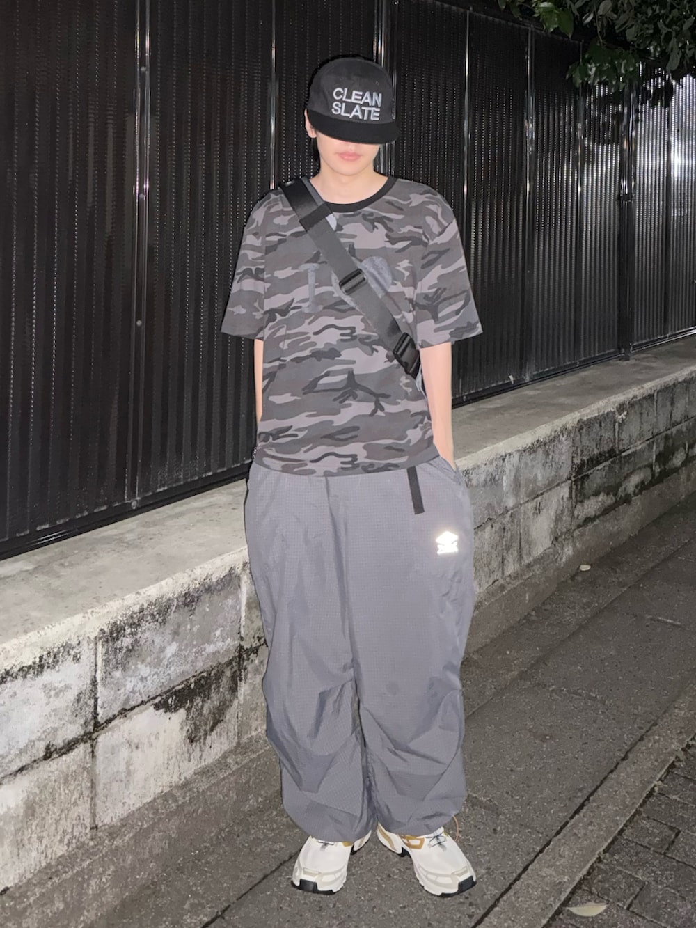 グレー系のショルダーバッグ、ホワイト系のスニーカー、グレー系のカーゴパンツを着用したメンズの夏コーディネートの2枚目の写真