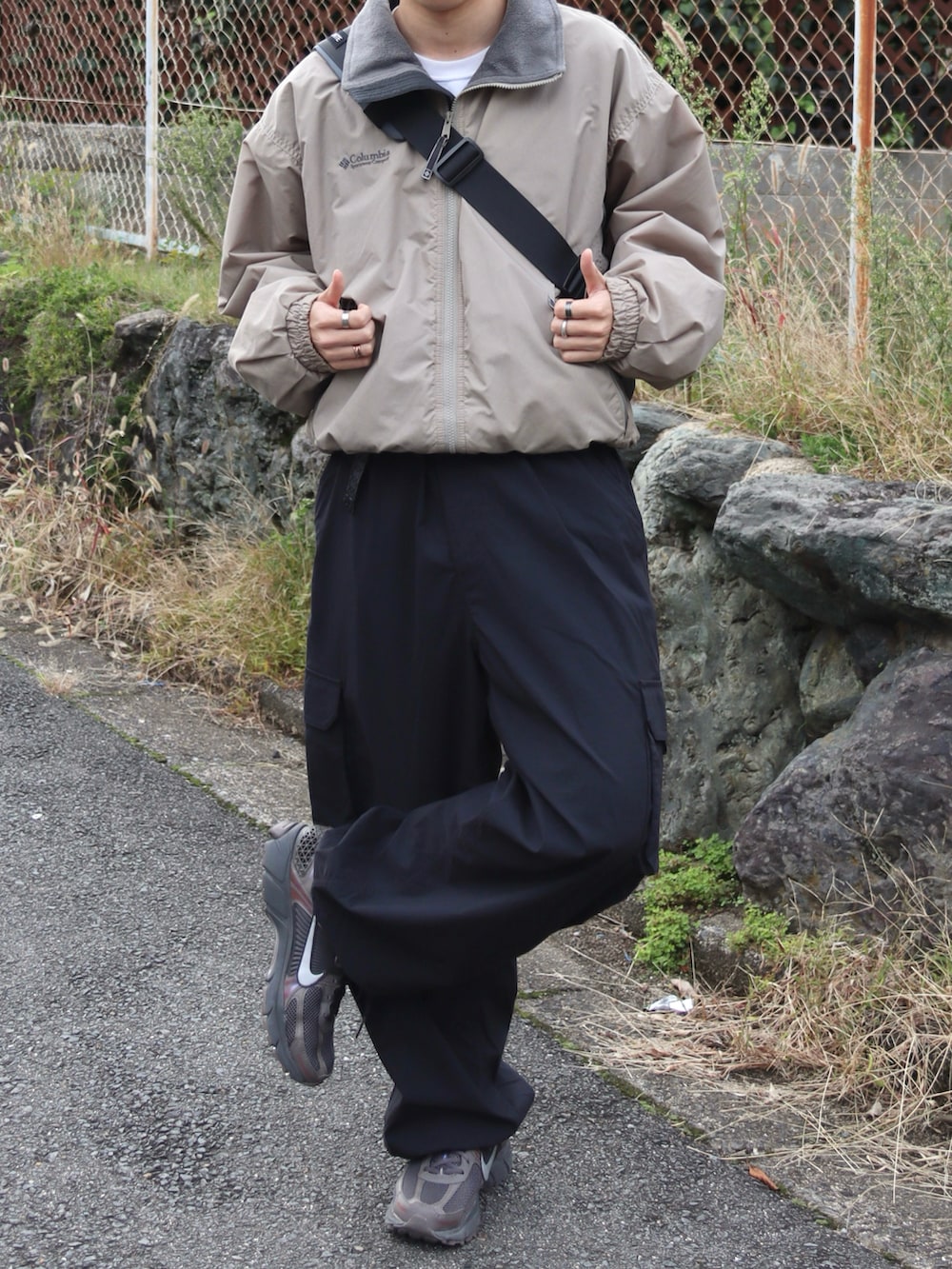 グレー系のショルダーバッグ、グレー系のスニーカー、ブラック系のカーゴパンツを着用したメンズの秋コーディネートの4枚目の写真