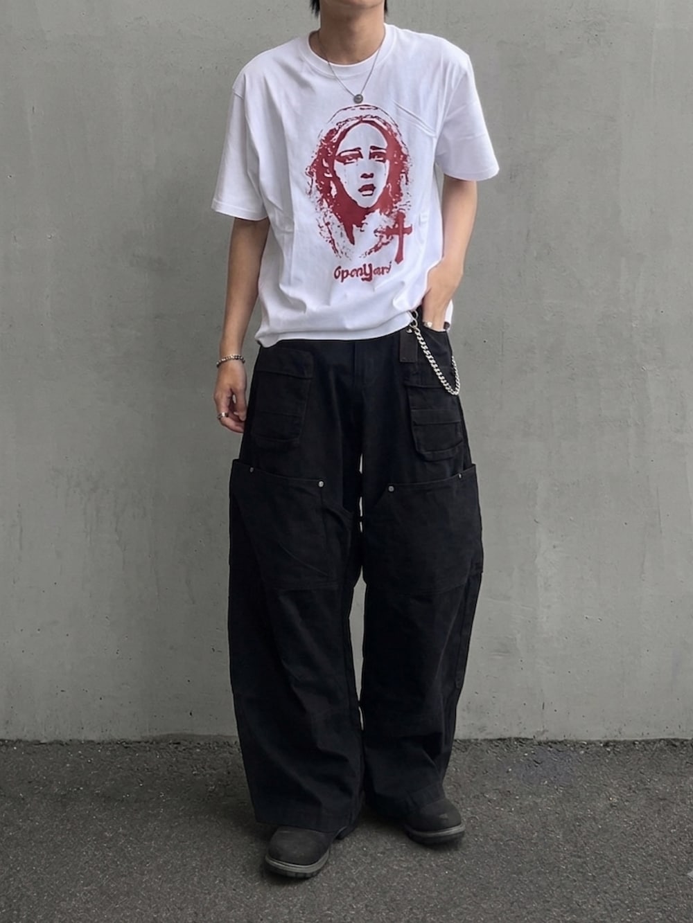 ブラック系のブーツ、ホワイト系のTシャツ/カットソー、グリーン系のカーゴパンツを着用したメンズの夏コーディネートの3枚目の写真