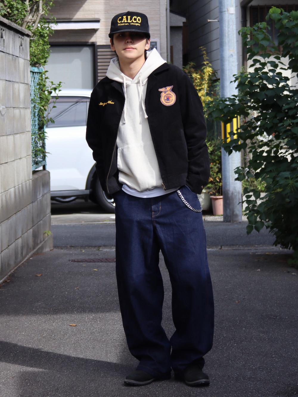 ベージュ系のパーカー、ホワイト系のタンクトップ、ブラック系のミリタリージャケットを着用したメンズの秋コーディネートの2枚目の写真