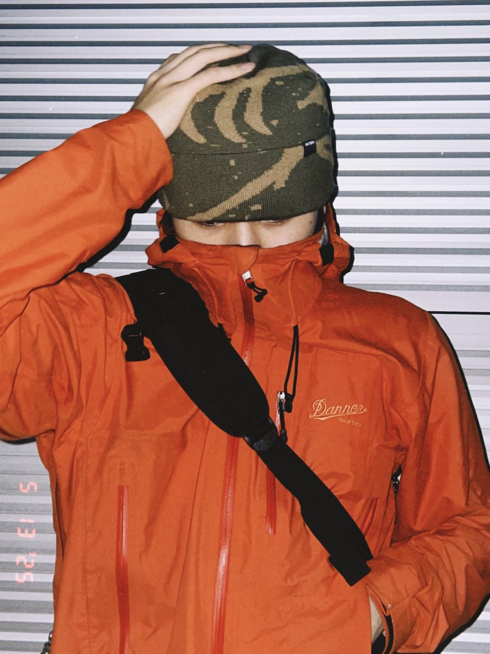 オレンジ系のマウンテンパーカー、グリーン系のニットキャップ/ビーニーを着用したメンズの春コーディネートの2枚目の写真