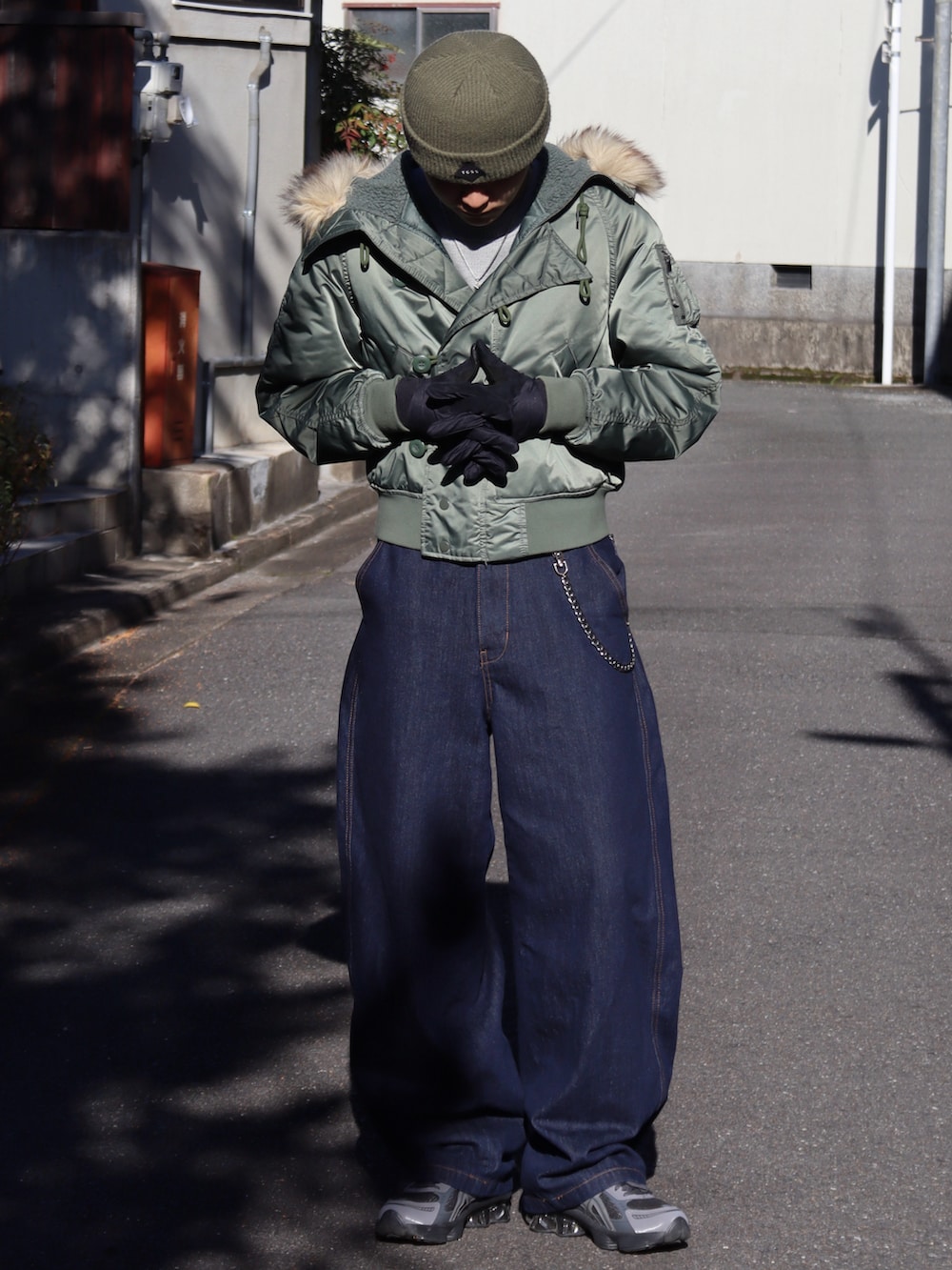 グレー系のスニーカー、グレー系のトップス、グリーン系のミリタリージャケットを着用したメンズの秋コーディネートの3枚目の写真