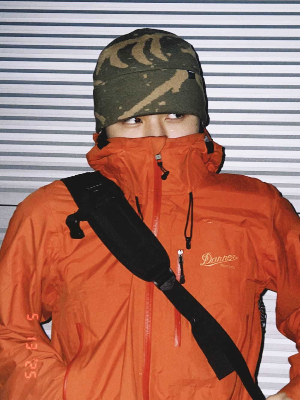 オレンジ系のマウンテンパーカー、グリーン系のニットキャップ/ビーニーを着用したメンズの春コーディネートの3枚目の写真