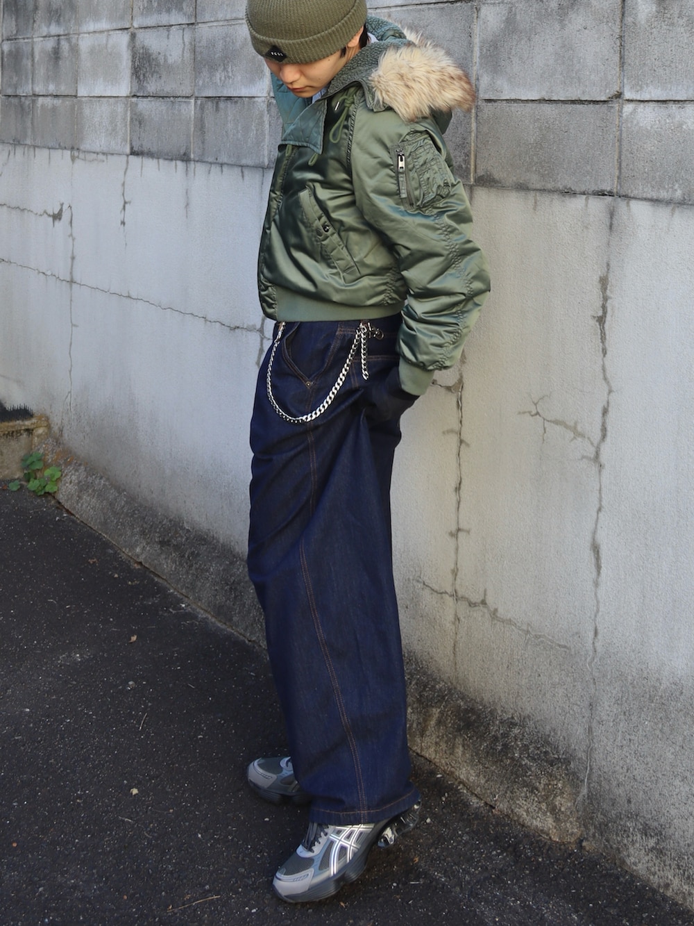 グレー系のスニーカー、グレー系のトップス、グリーン系のミリタリージャケットを着用したメンズの秋コーディネートの4枚目の写真