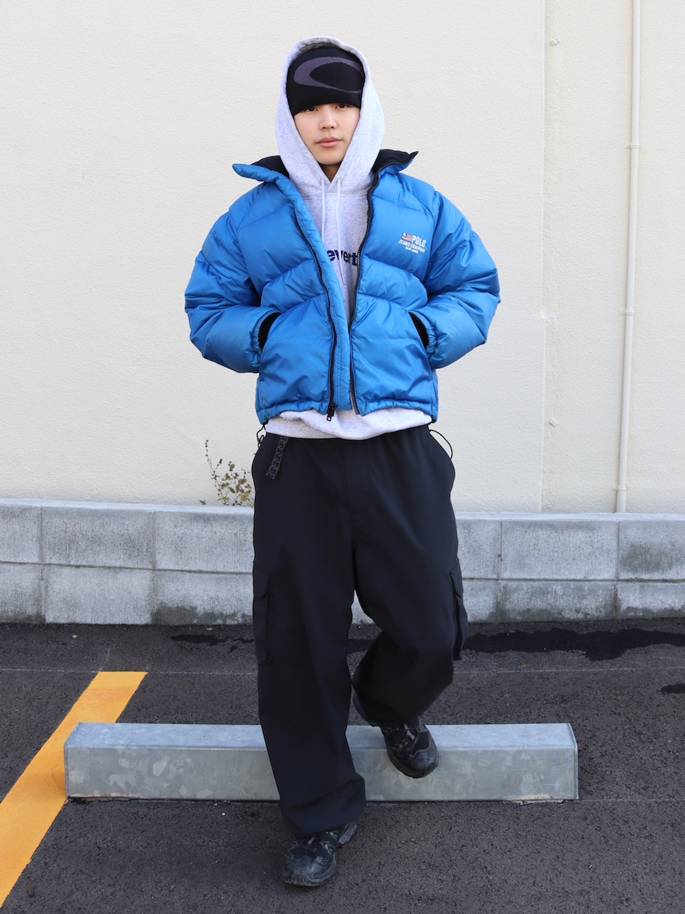 グレー系のパーカー、ブラック系のカーゴパンツ、ブラック系のスニーカーを着用したメンズの冬コーディネートの2枚目の写真