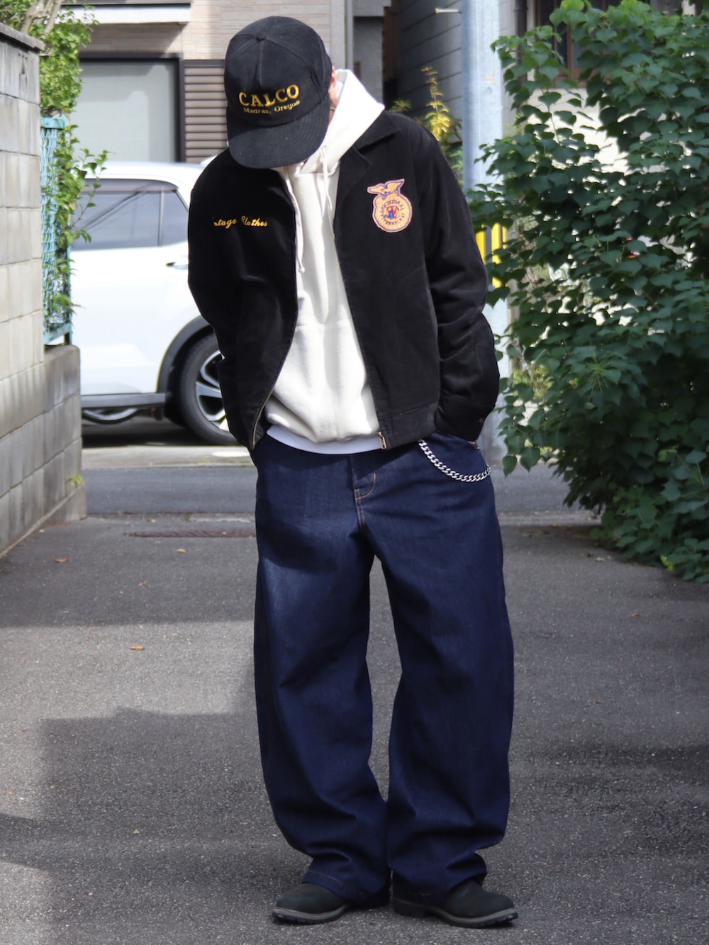 ベージュ系のパーカー、ホワイト系のタンクトップ、ブラック系のミリタリージャケットを着用したメンズの秋コーディネートの4枚目の写真