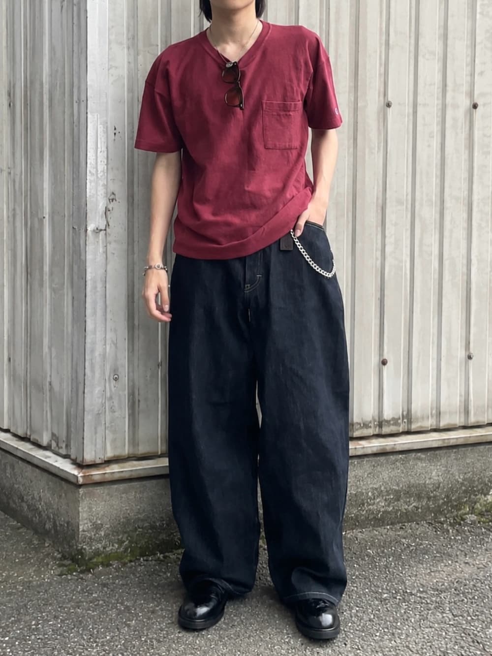 ブルー系のデニムパンツ、ブラック系のドレスシューズ、レッド系のTシャツ/カットソーを着用したメンズの夏コーディネートの2枚目の写真
