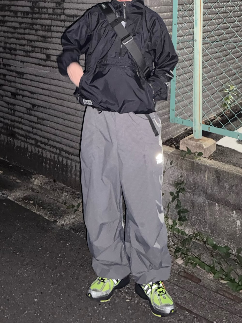 グレー系のショルダーバッグ、グレー系のカーゴパンツ、グリーン系のスニーカーを着用したメンズの冬コーディネートの3枚目の写真