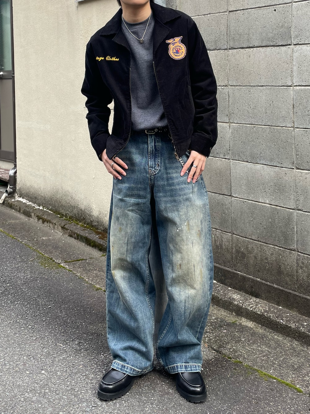 グレー系のスウェット、ブラック系のミリタリージャケット、ブルー系のデニムパンツを着用したメンズの春コーディネートの3枚目の写真