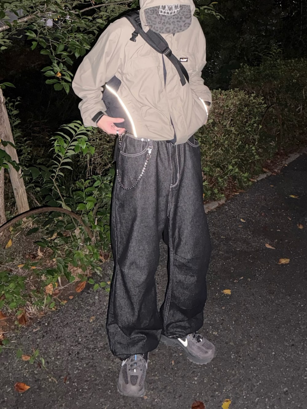 グレー系のスニーカー、ベージュ系のマウンテンパーカー、ブラック系のデニムパンツを着用したメンズの秋コーディネートの3枚目の写真