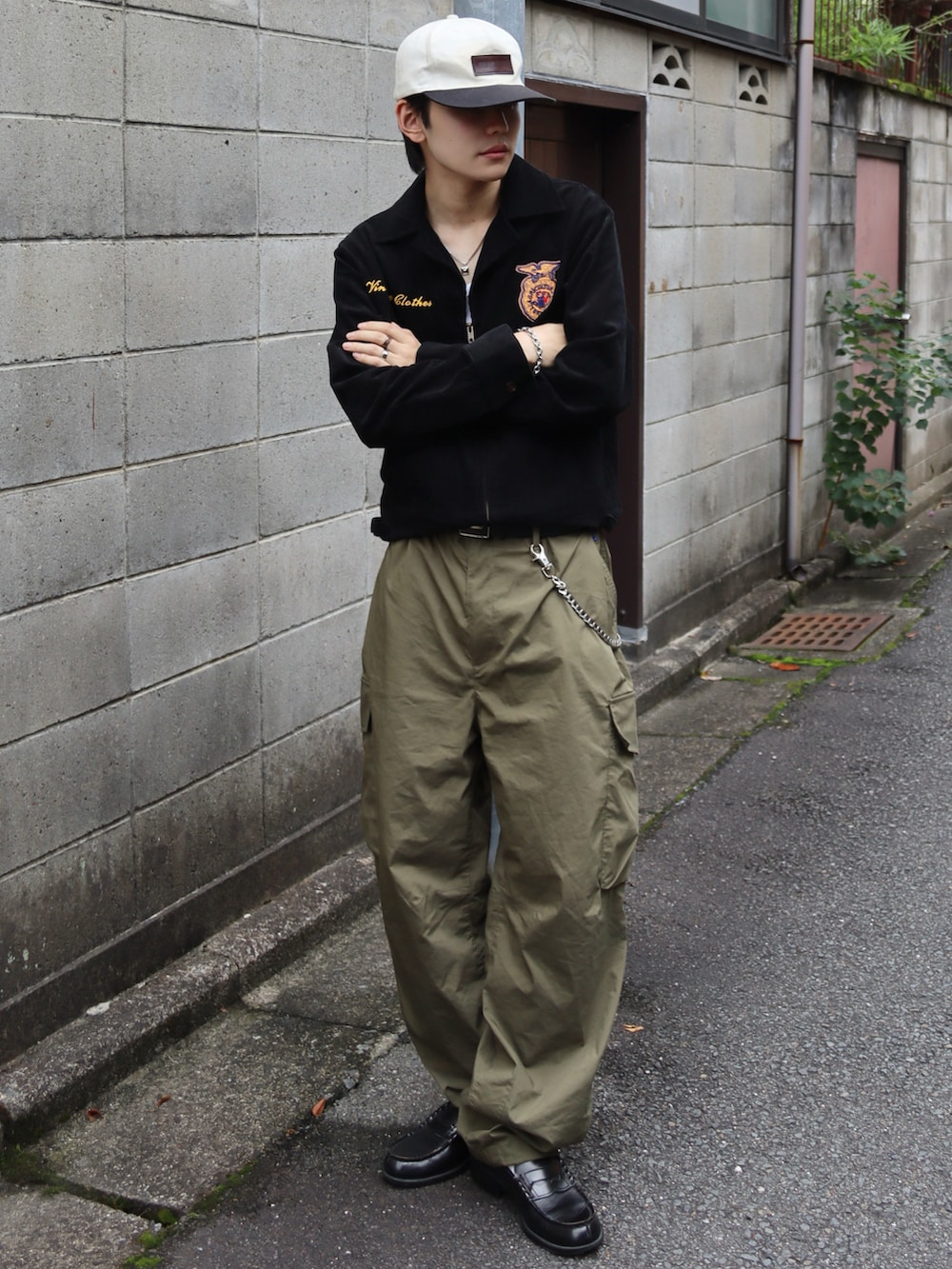 ホワイト系のタンクトップ、グリーン系のカーゴパンツ、ブラック系のミリタリージャケットを着用したメンズの秋コーディネートの2枚目の写真