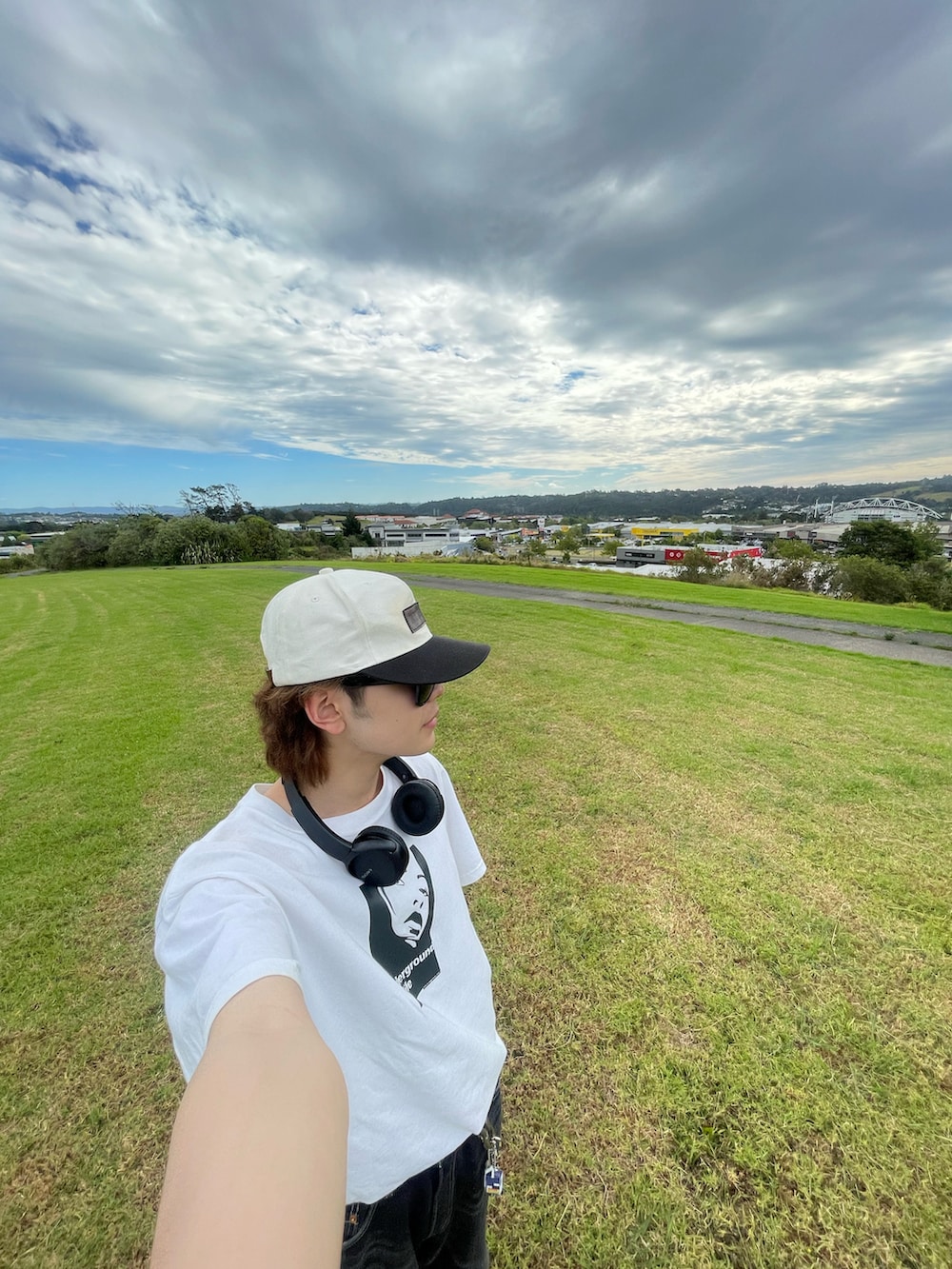 ブラック系のスニーカー、ホワイト系のTシャツ/カットソー、ブラック系のデニムパンツを着用したメンズの夏コーディネートの3枚目の写真