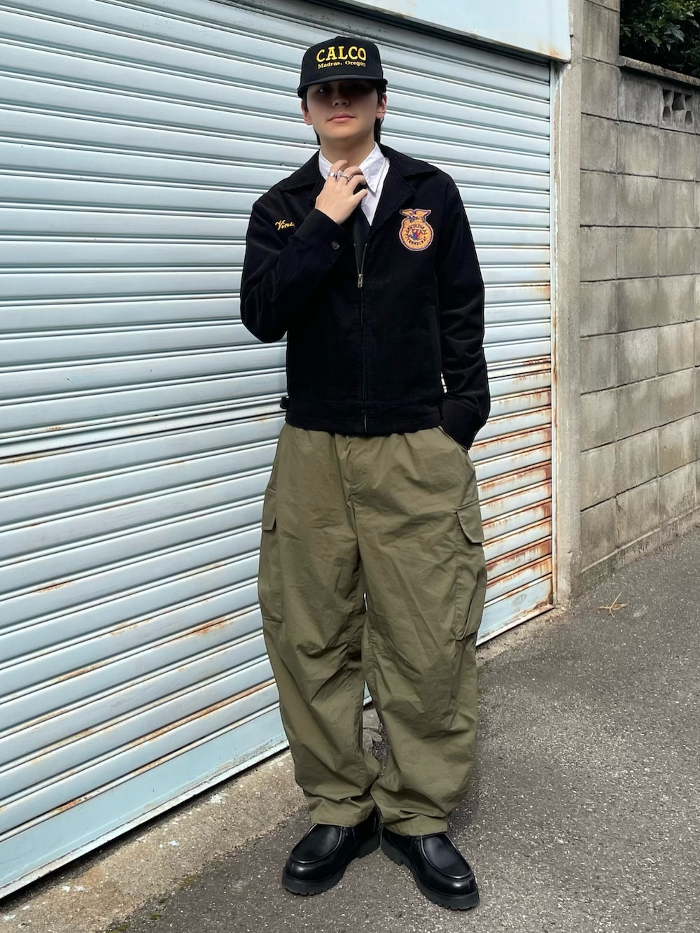 ブラック系のミリタリージャケット、グリーン系のカーゴパンツ、ブラック系のドレスシューズを着用したメンズの春コーディネートの2枚目の写真
