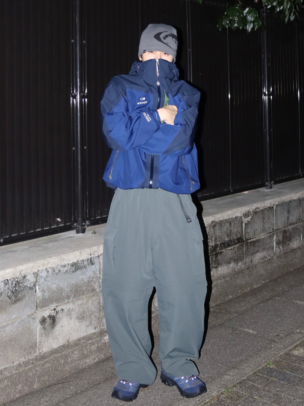 グレー系のスニーカー、ブルー系のマウンテンパーカー、グリーン系のカーゴパンツを着用したメンズの秋コーディネートの2枚目の写真