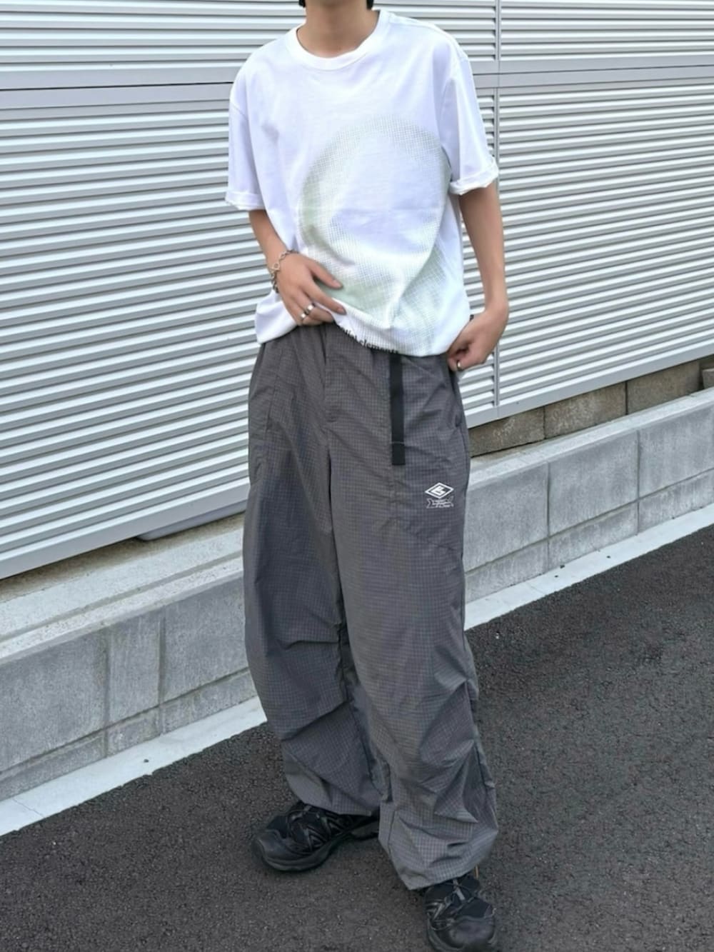 グレー系のカーゴパンツ、ブラック系のスニーカー、ホワイト系のTシャツ/カットソーを着用したメンズの夏コーディネートの2枚目の写真