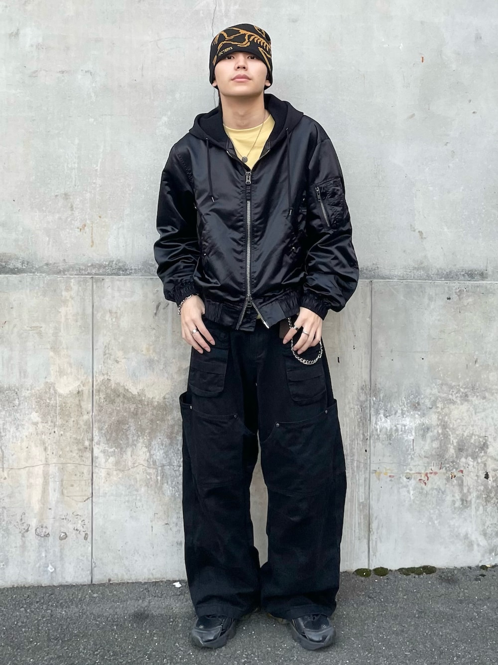 ブラック系のブルゾン、イエロー系のTシャツ/カットソー、ブラック系のカーゴパンツを着用したメンズの秋コーディネートの2枚目の写真