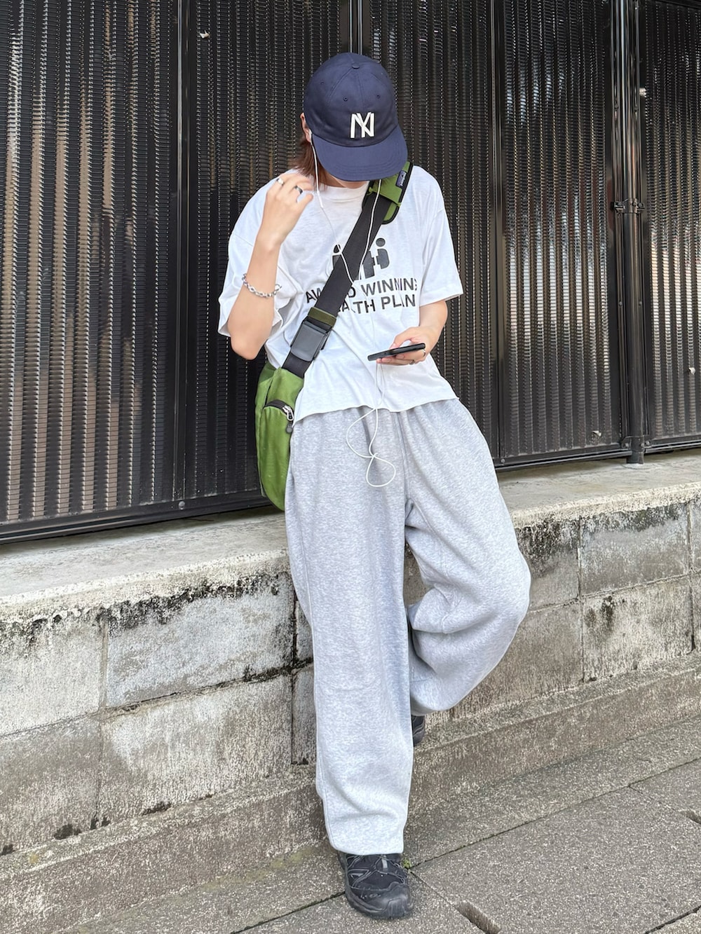 ホワイト系のTシャツ/カットソー、グリーン系のメッセンジャーバッグ、グレー系のスウェットパンツを着用したメンズの夏コーディネートの2枚目の写真