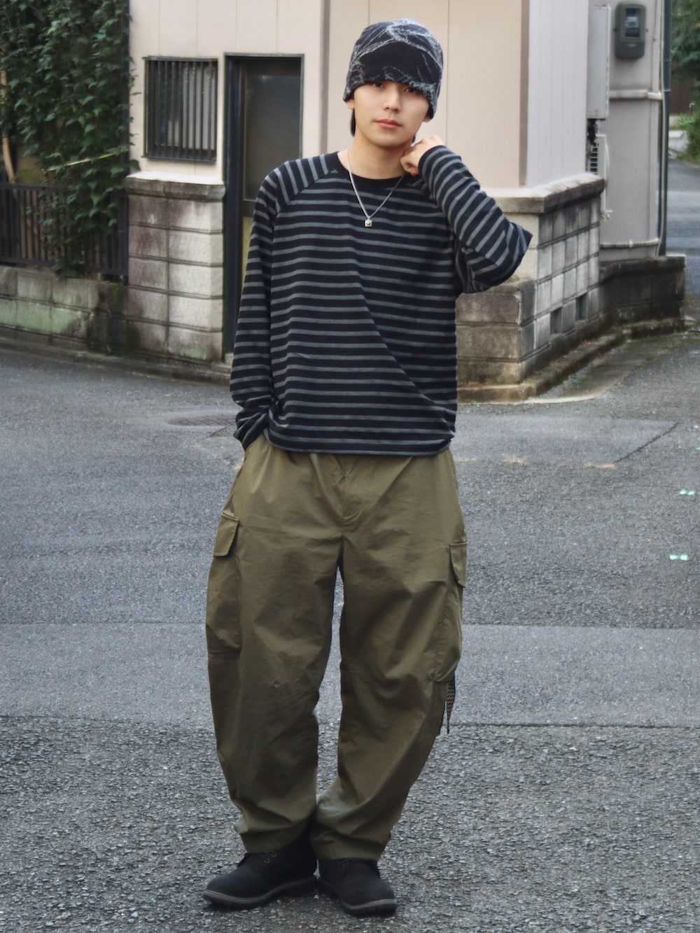 グリーン系のカーゴパンツ、ブラック系のブーツ、その他のTシャツ/カットソーを着用したメンズの秋コーディネートの2枚目の写真