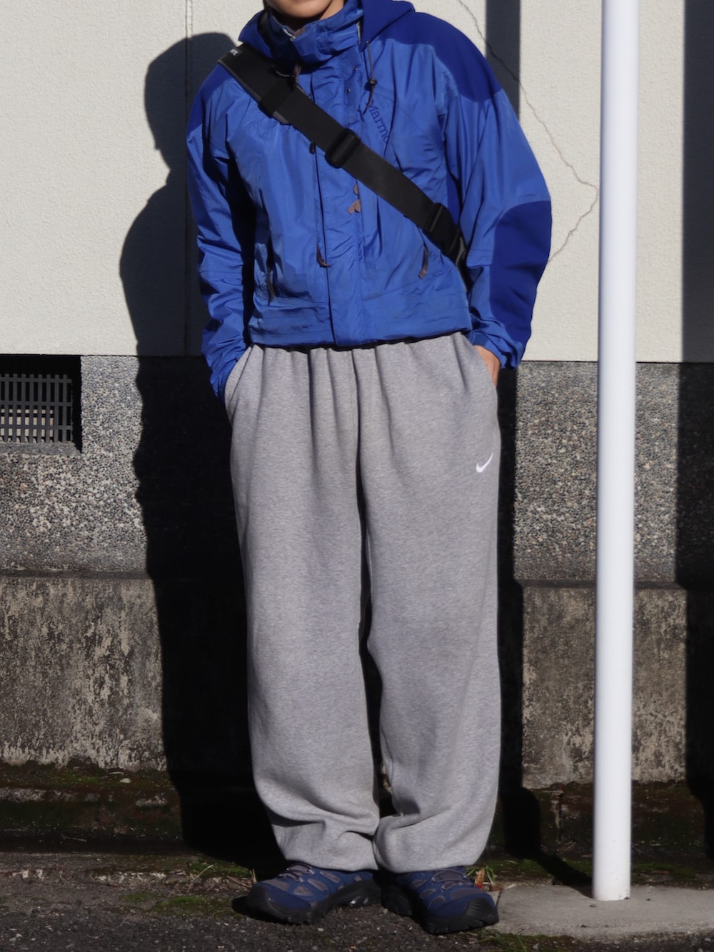 グレー系のスニーカー、グレー系のショルダーバッグ、ブルー系のジャケット/アウターを着用したメンズの秋コーディネートの3枚目の写真