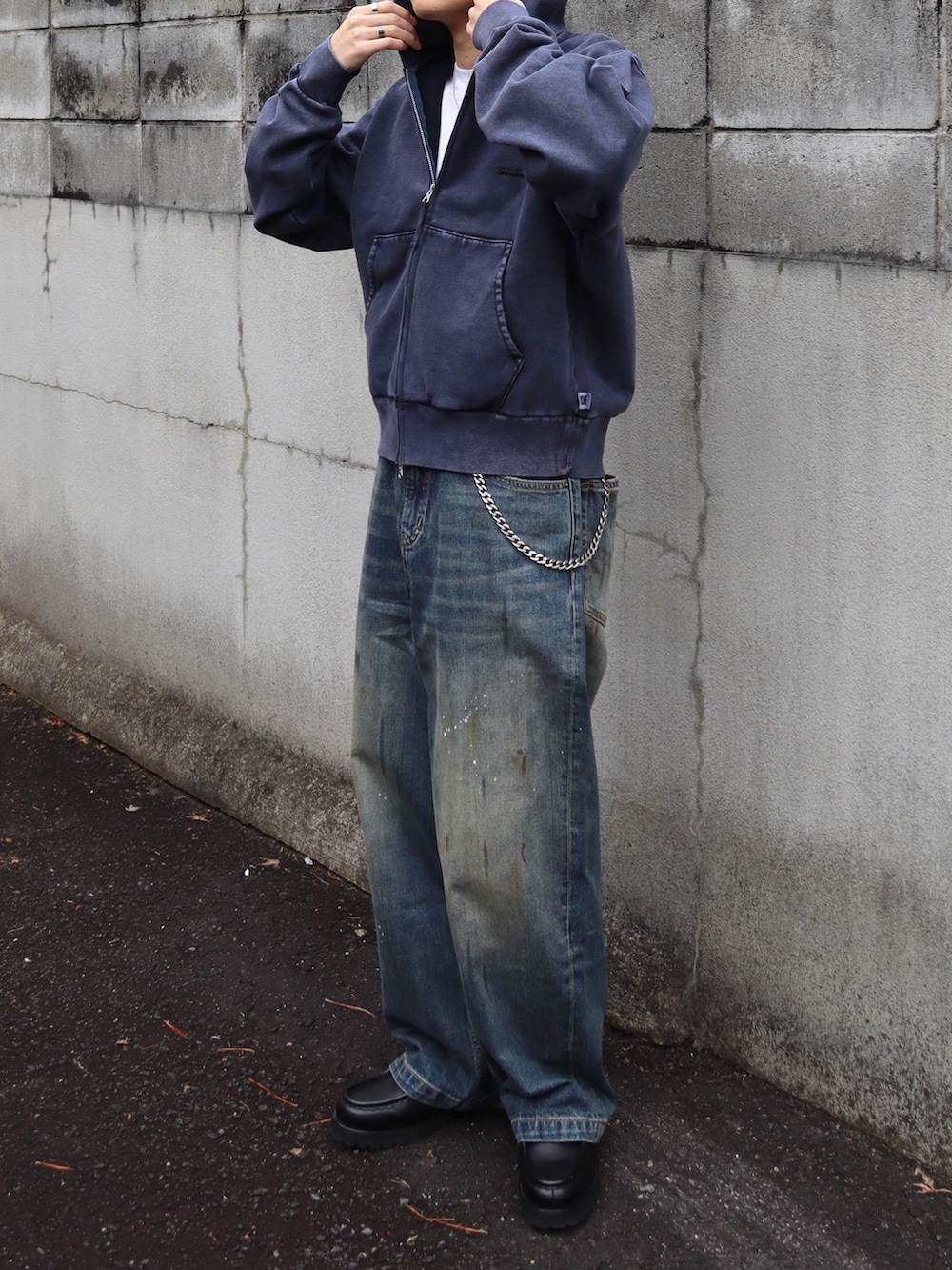 ブルー系のパーカー、ブラック系のドレスシューズ、ブルー系のデニムパンツを着用したメンズの春コーディネートの3枚目の写真